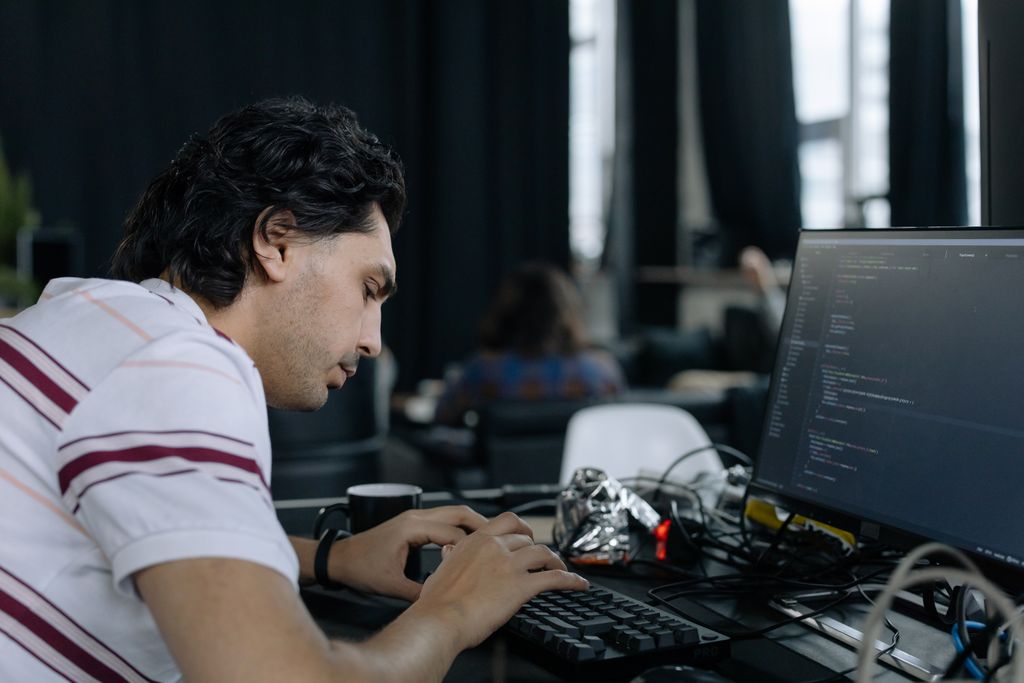 A coder intensely typing at a workstation in a contemporary office to symbolise jobs in AI