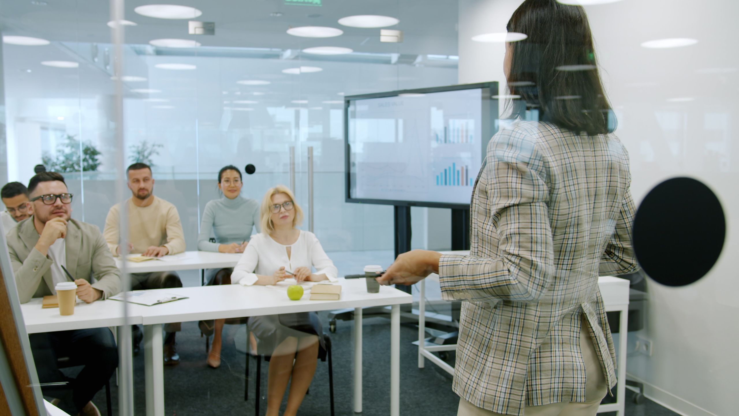Businesswoman presenting to attentive audience in a modern office.