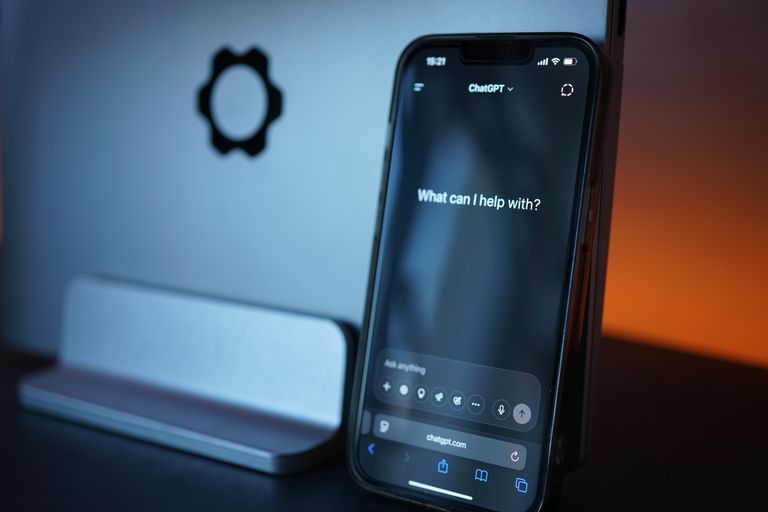 Close-up of a smartphone with AI chat interface, saying 'how can I help' to symbolise workplace wellbeing shifting with technology.