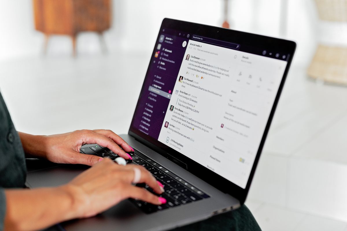 Woman typing on a laptop that shows a team messaging app