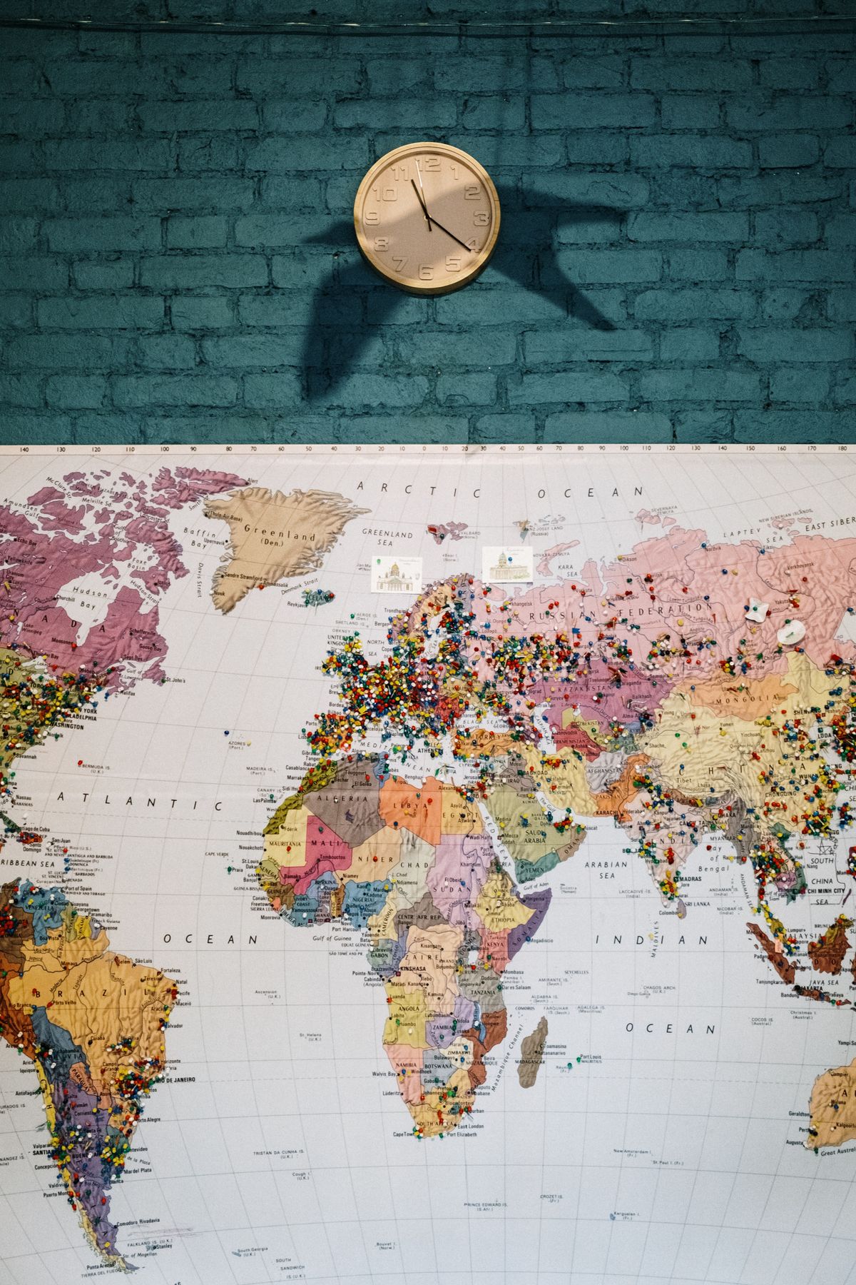 World map on a blue wall with colourful pins marking locations
