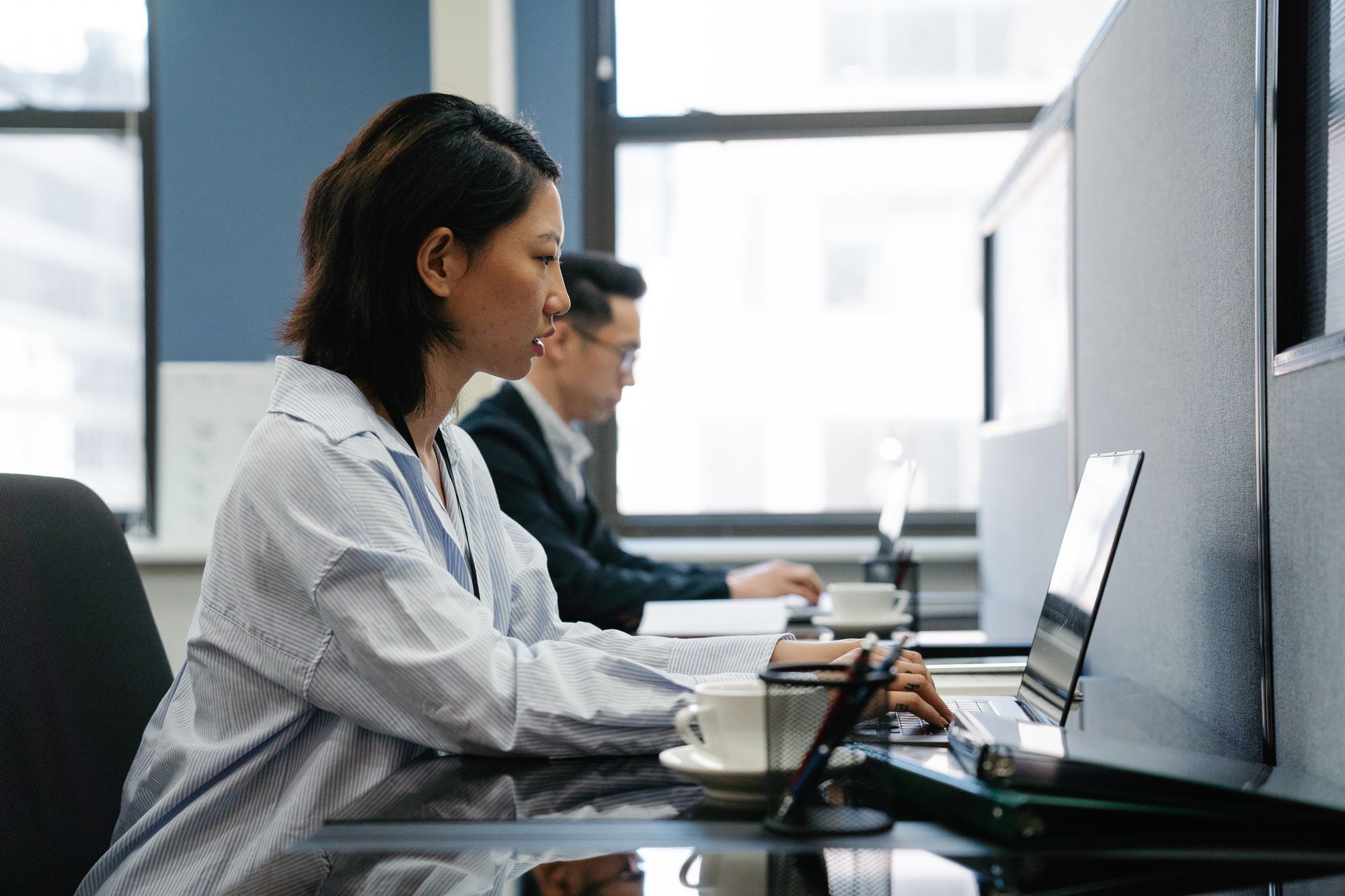 Two employees working on laptops in an office, AI adoption and workload
