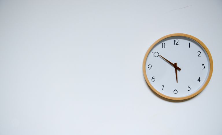 Simple wall clock with wooden frame against a white background, showing the time 10:10.